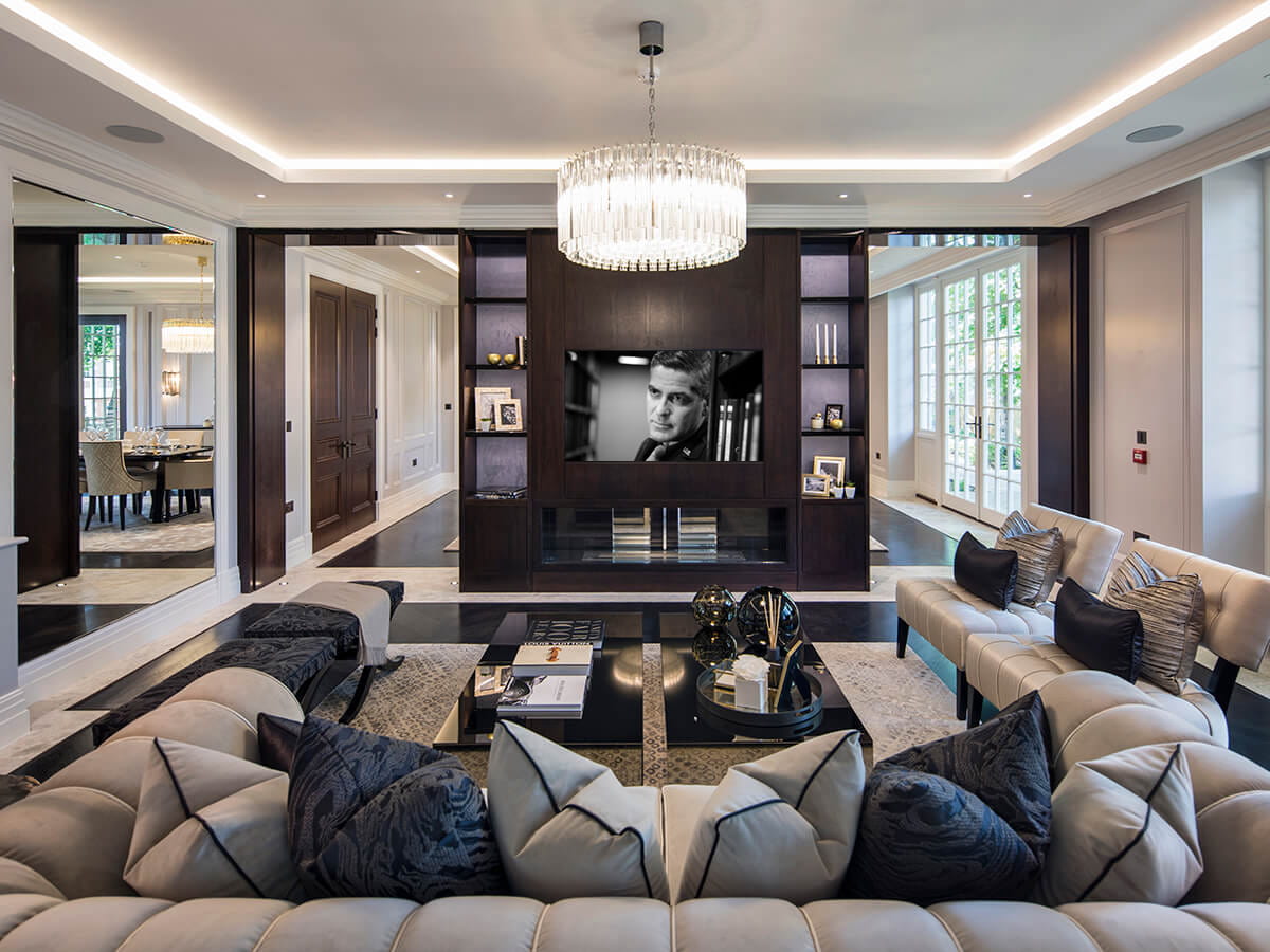 Luxurious living room featuring a plush sectional sofa, a modern coffee table, and a large flat-screen TV mounted on a dark wood entertainment unit, with a chan