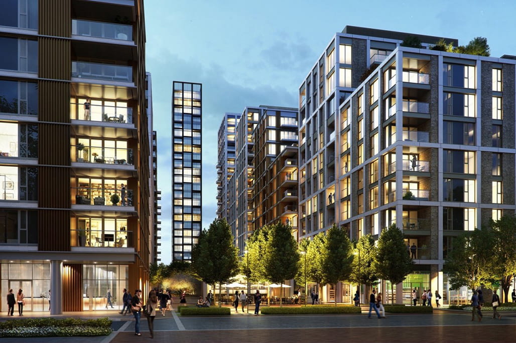 Modern residential buildings with large windows and balconies, surrounded by trees and people in an urban setting during twilight.