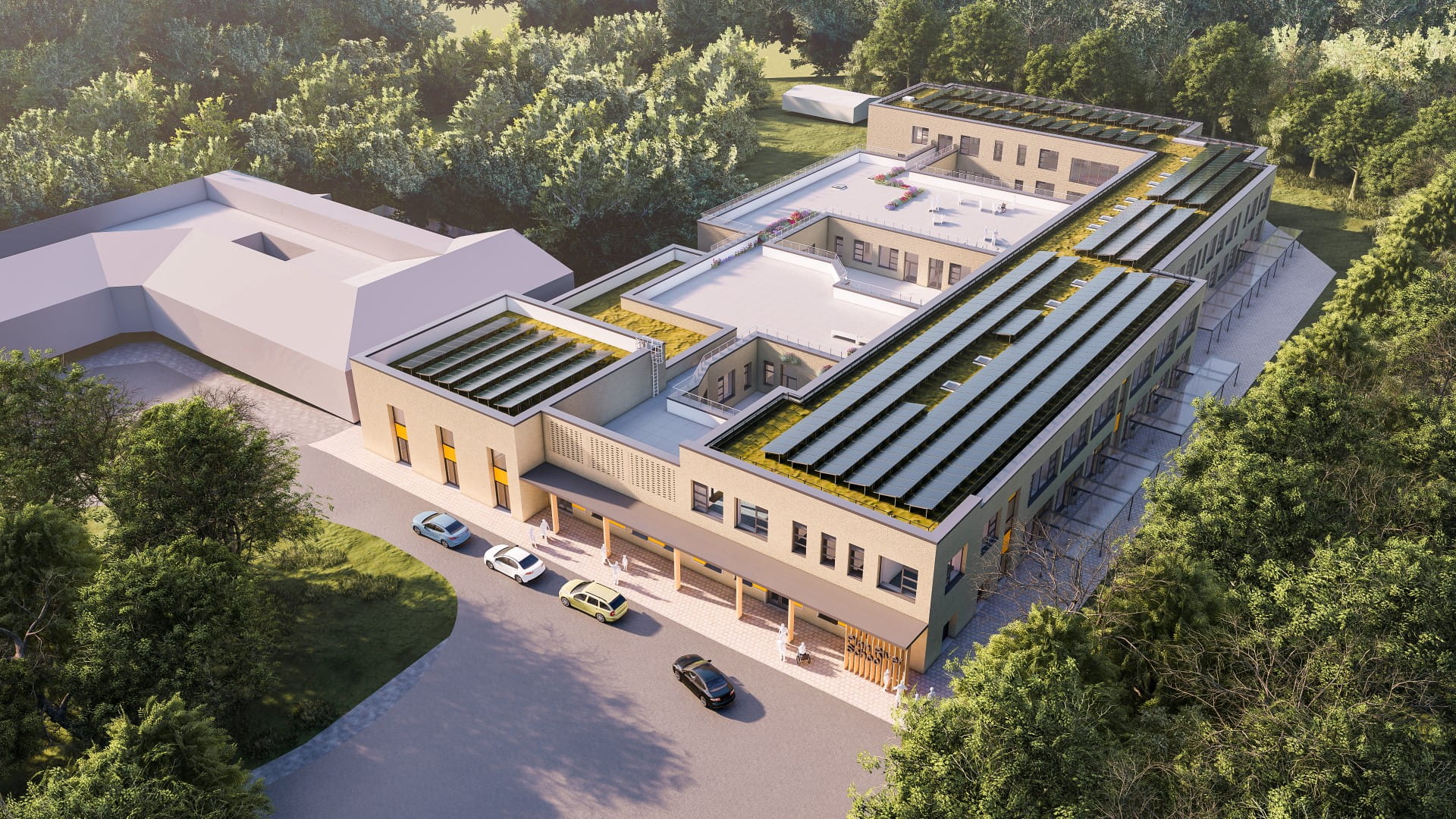 Aerial view of a modern building with a green roof and solar panels, surrounded by trees and a parking area.