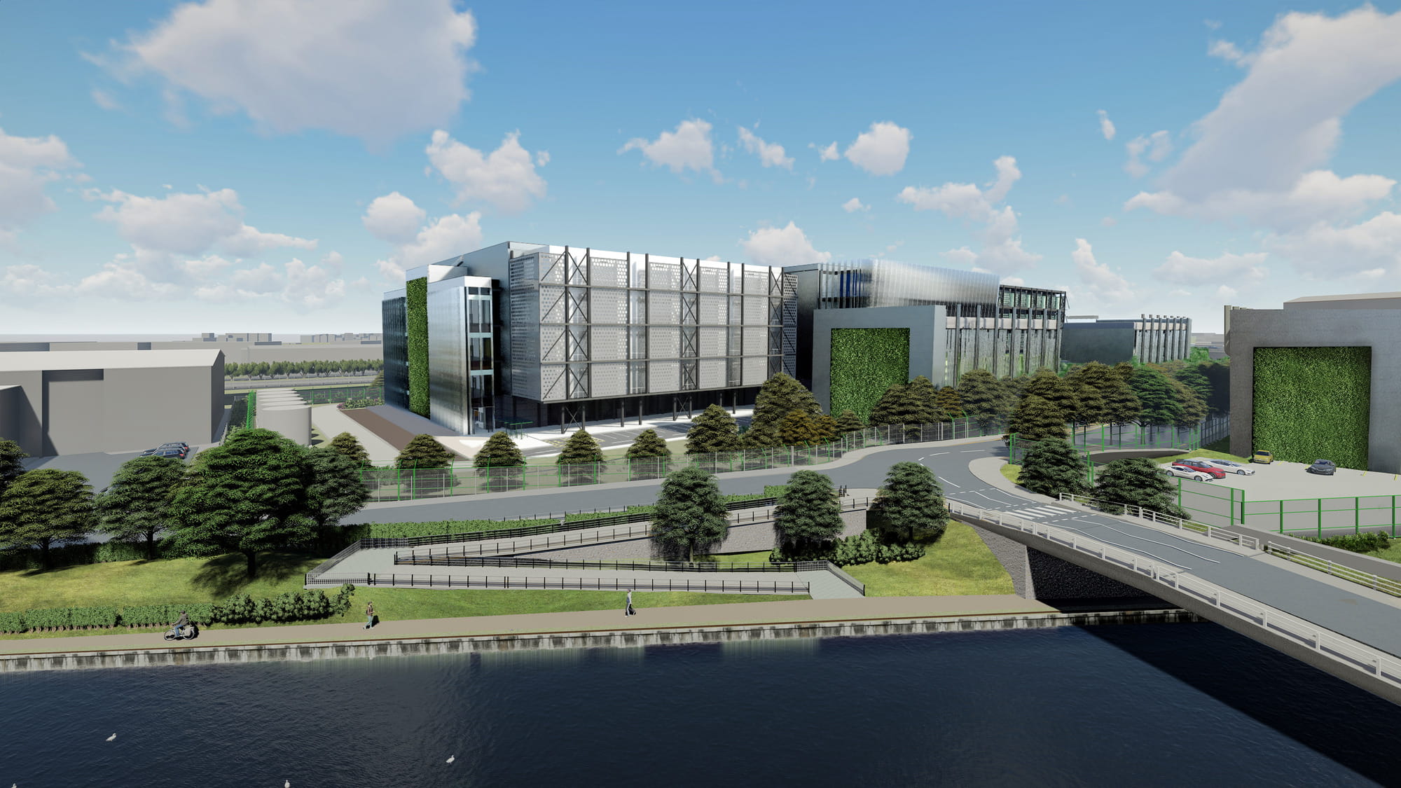 A modern data center building with a glass facade, surrounded by greenery, alongside a river and a road with parked cars and pedestrians.