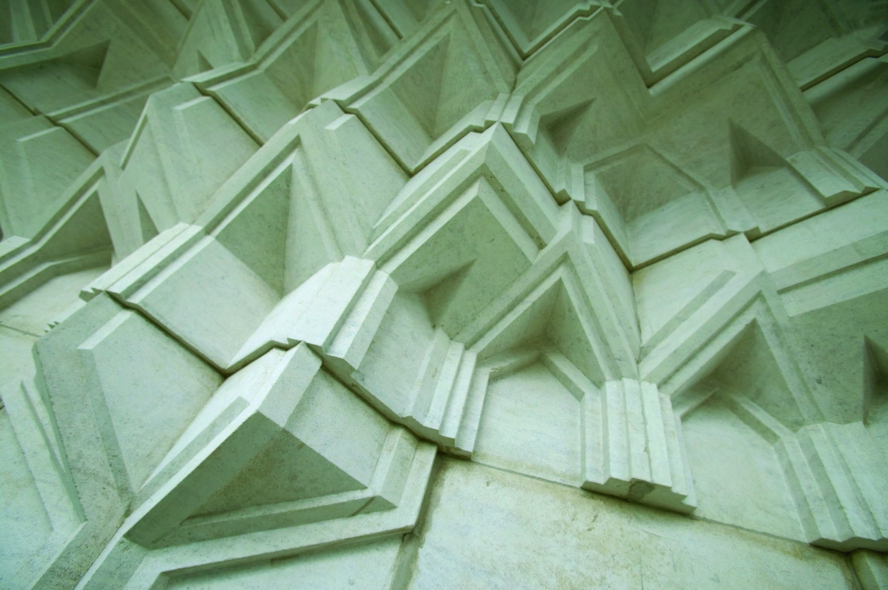 Textured architectural wall featuring geometric patterns and angular shapes in light-colored material.