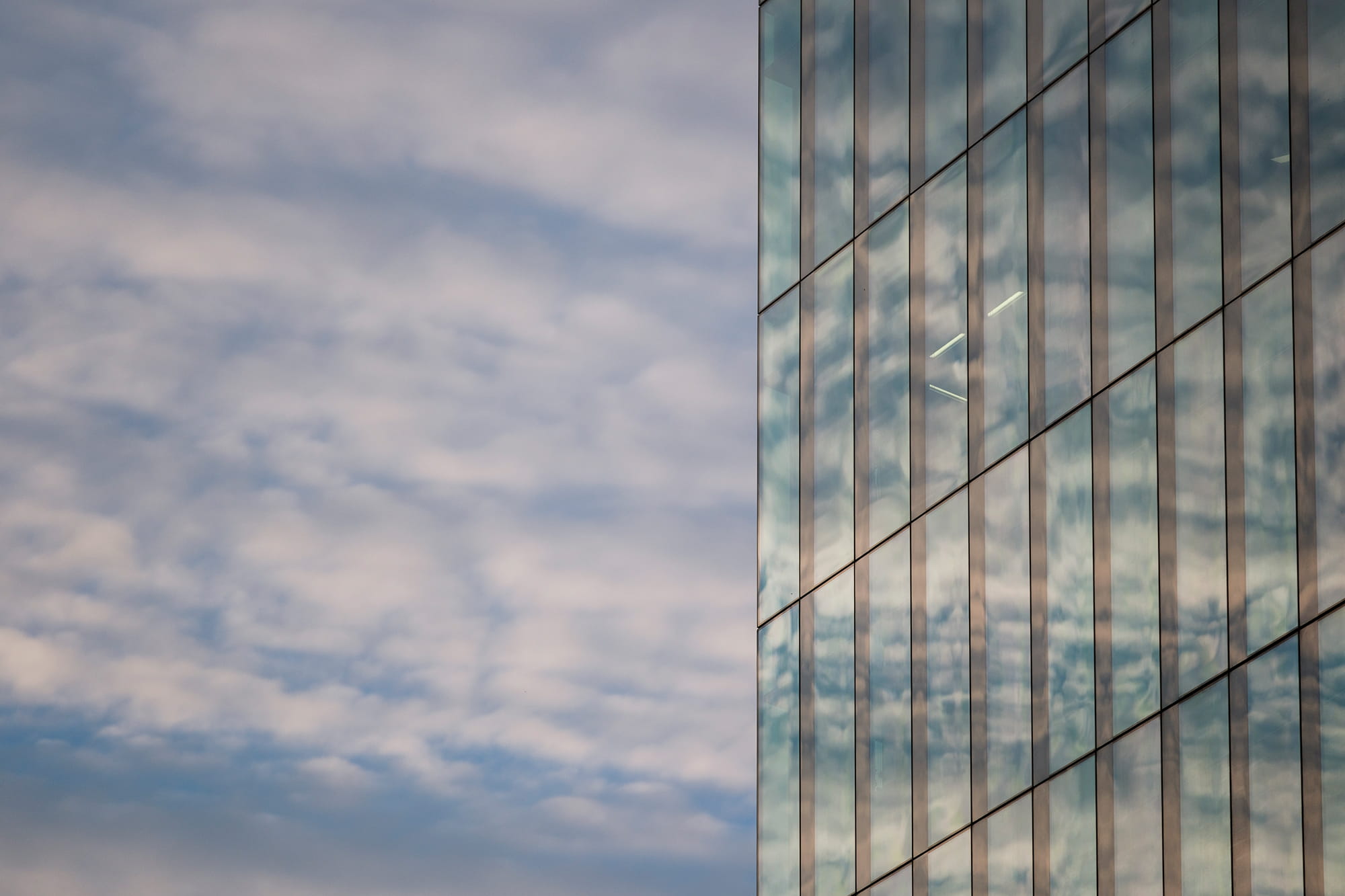 Reflection of clouds on the glass facade of a modern building.