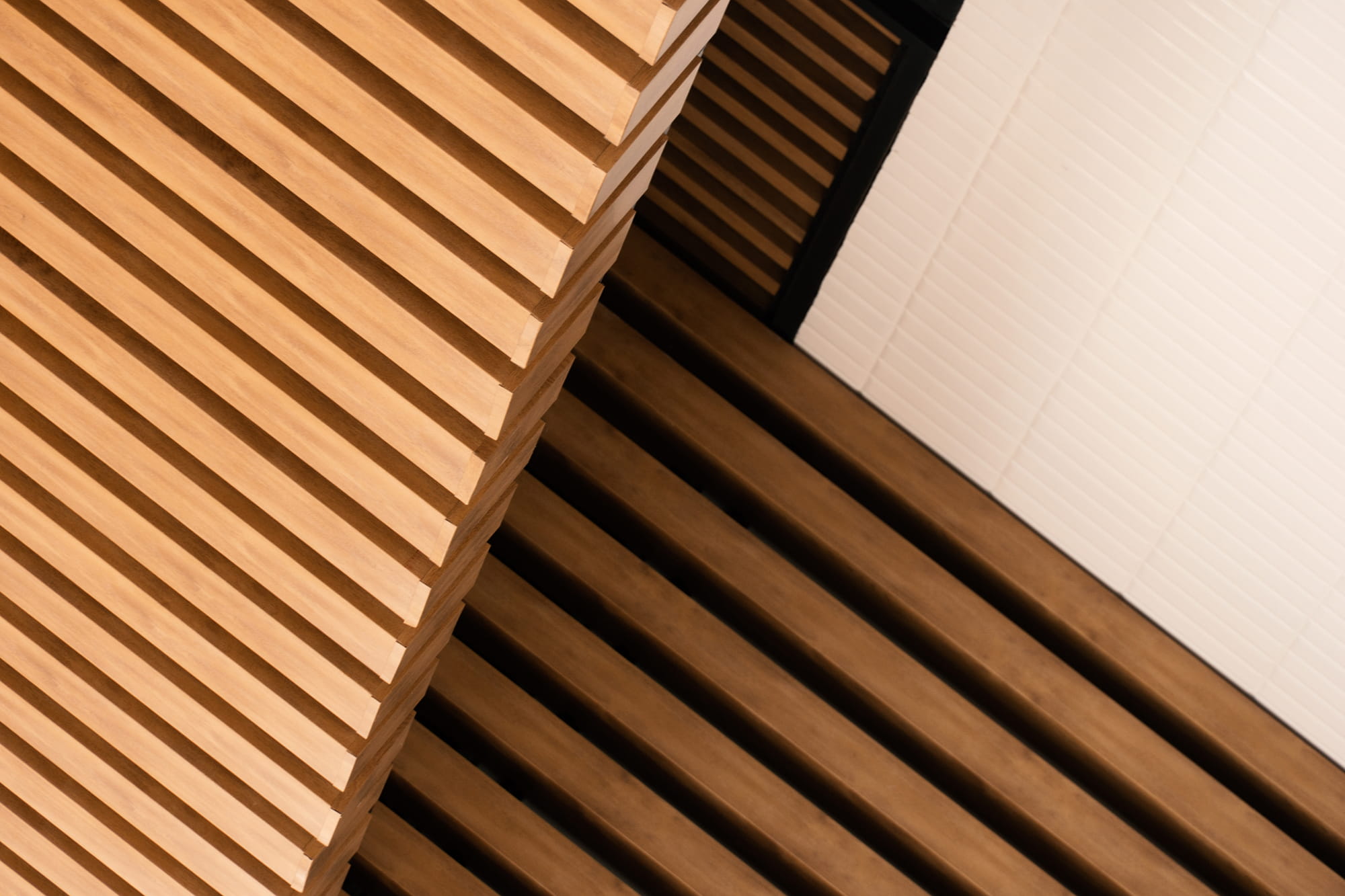 Diagonal view of wooden slatted panels intersecting with a flat white surface.