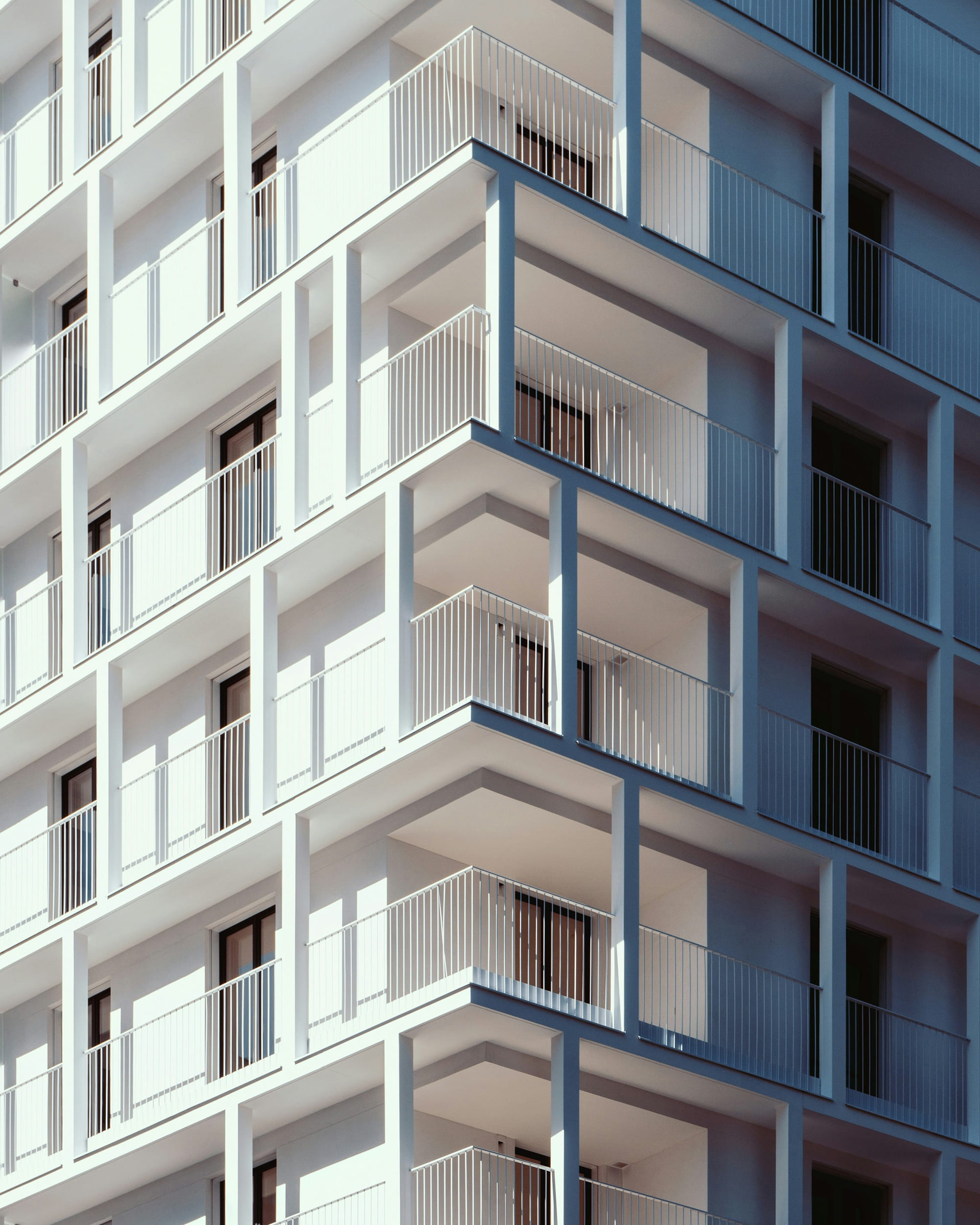 Modern apartment building facade featuring multiple balconies and large windows.