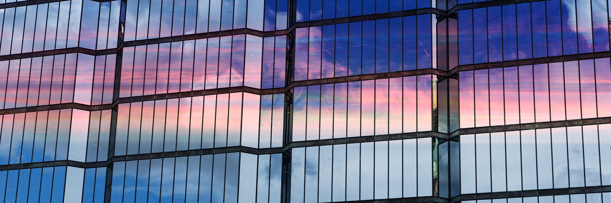 Reflections of a colorful sunset on the glass facade of a modern building.
