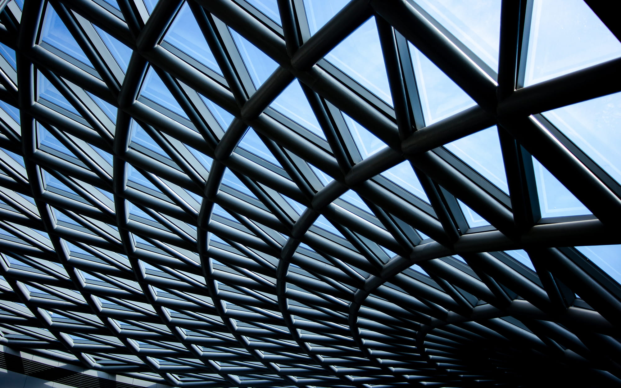 Geometric glass and metal ceiling structure with a grid pattern, allowing natural light to filter through.