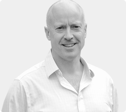 Smiling man in a light-colored shirt against a neutral background.