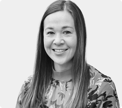 Smiling woman with long hair wearing a floral blouse against a light background.