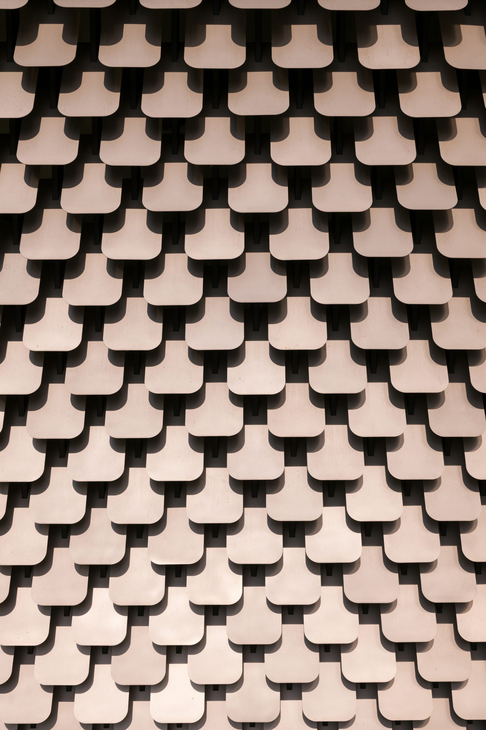 Patterned wall featuring overlapping, curved metal panels arranged in a grid formation.